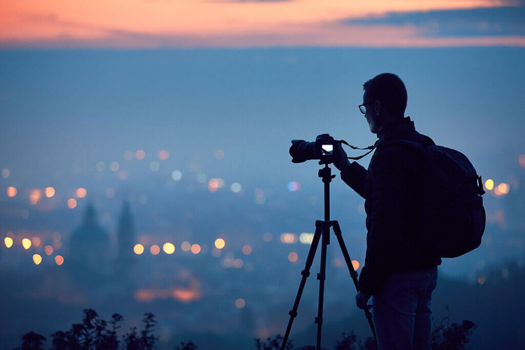 A photographer with his tripod overtop the city.
