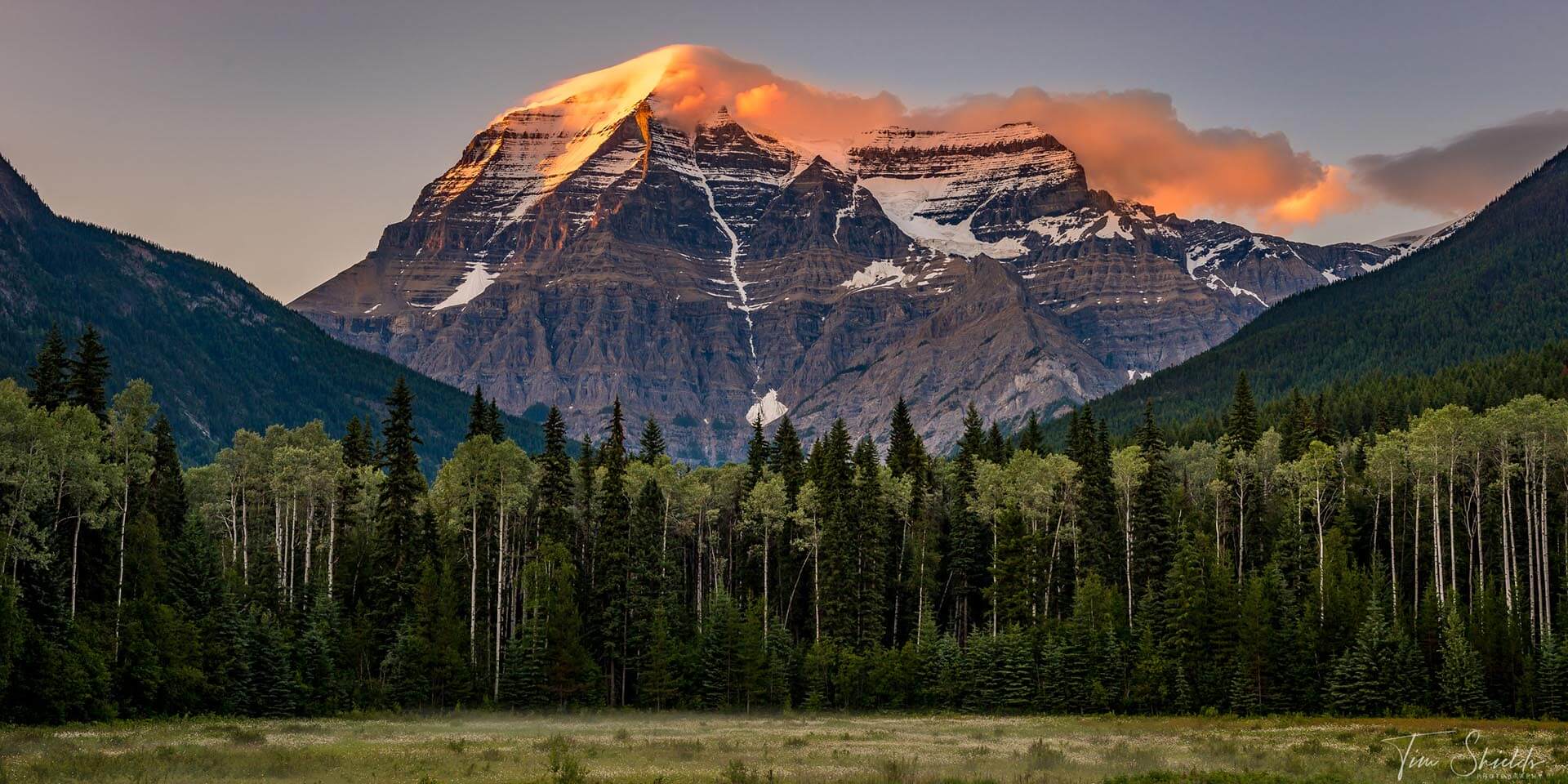 A photo of an iconic mountain in Banff National Park with the peak lit up with the dramatic, last light of day