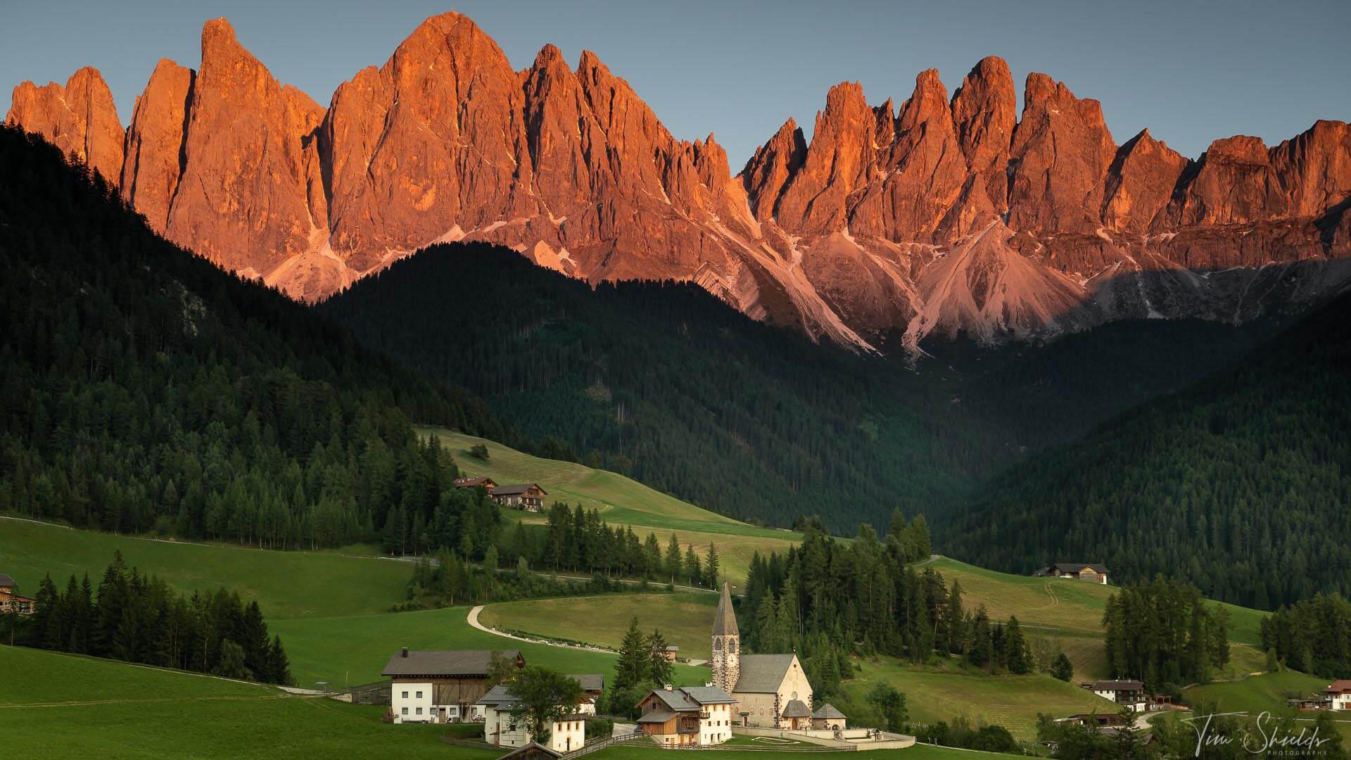 A photograph of a small village just below an iconic mountainous landscape